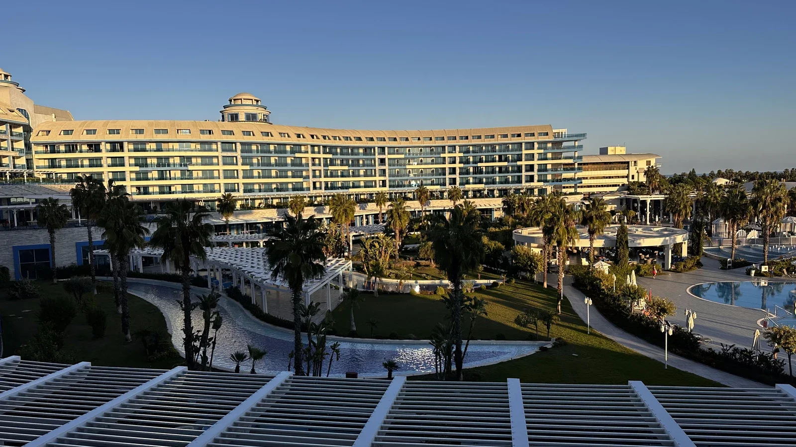 Golfresort med pool, palmer og hotelbygning i aftenlys i Belek, Tyrkiet