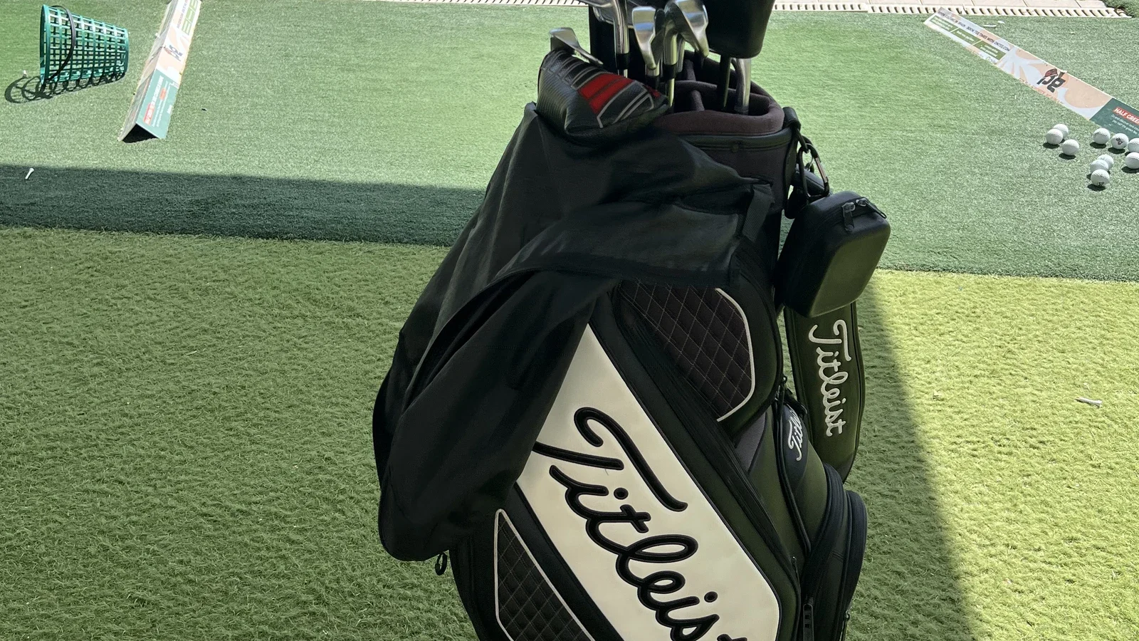 Golftaske med jern og driver på en driving range i aftenlys